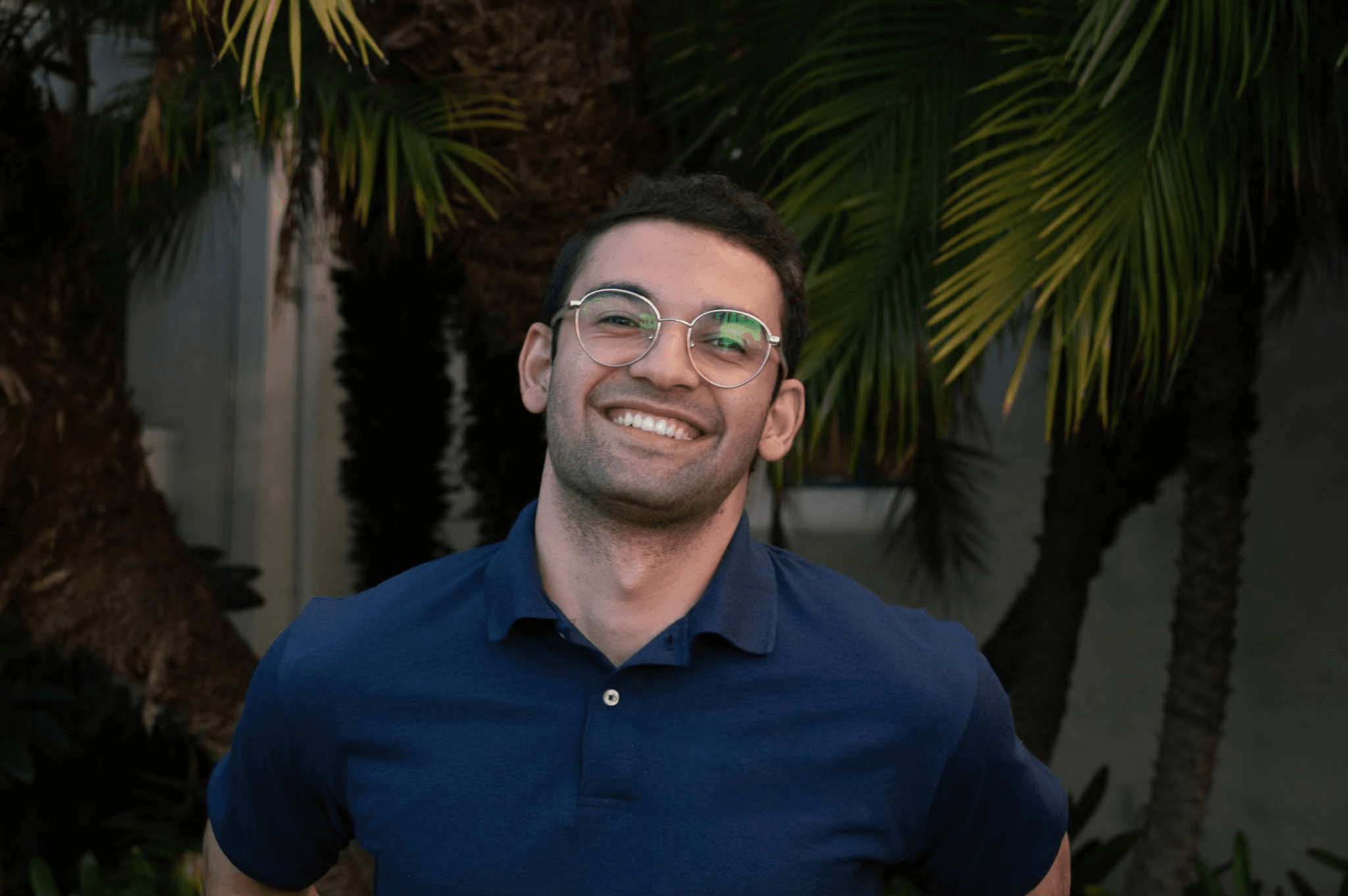 Mohammad Qudsi, smiling in front of palm trees